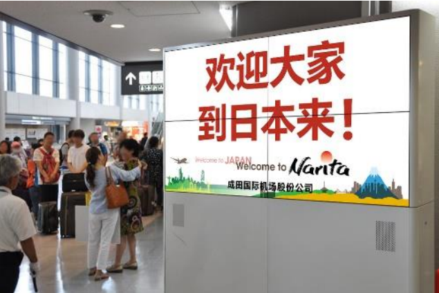 空港到着ロビーのデジタル看板で、特定訪日客向けの歓迎メッセージを表示、成田空港が無料で提供、MICE参加者向け